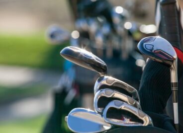 Two bags of golf clubs standing on a golf course