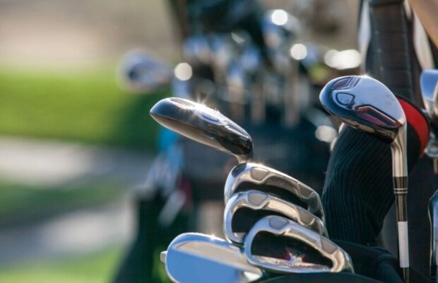 Two bags of golf clubs standing on a golf course