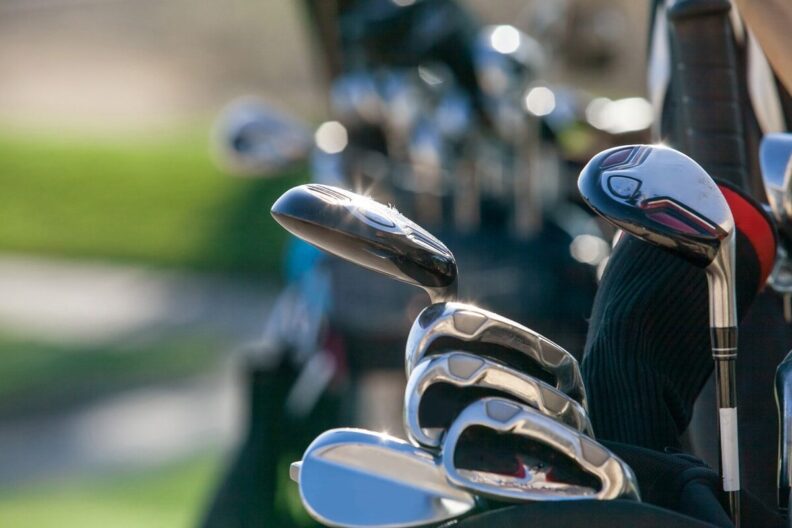 Two bags of golf clubs standing on a golf course