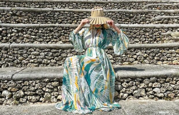 Woman in a long, flowy dress and woven hat on the steps of Altos de Chavón