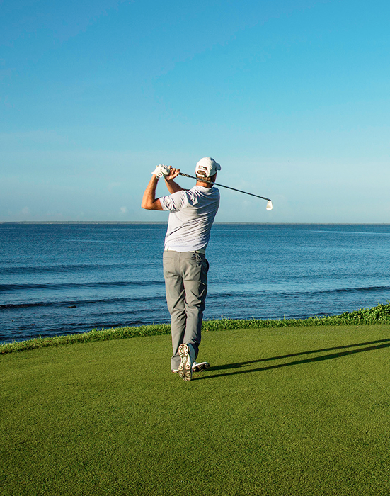 Golfer swinging away on the Teeth of the Dog golf course at Casa de Campo