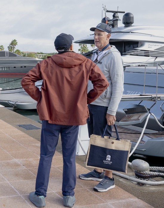Marina staff speaking with a boater beside a docked yacht
